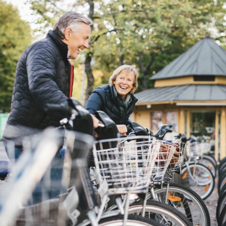 A middle-aged couple laughing while riding bicycles.