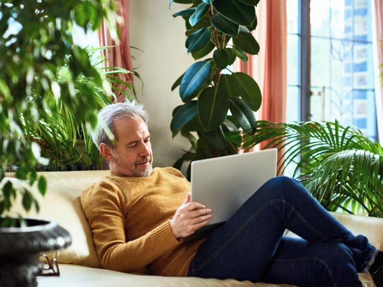 Mature man using laptop on sofa at home