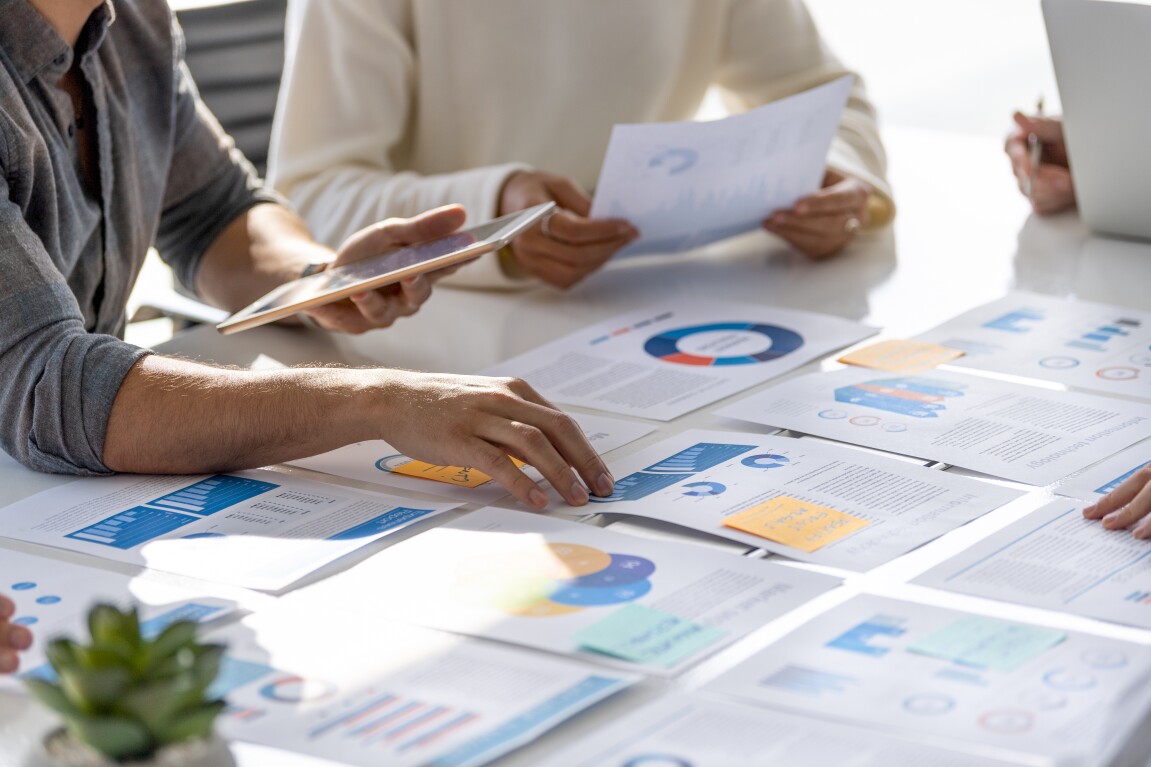 Multi racial group of people working with Paperwork on a board room table at a business presentation or seminar.