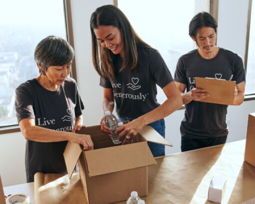 Three volunteers pack boxes of supplies