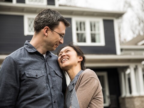 Couple standing in front of home looking happy