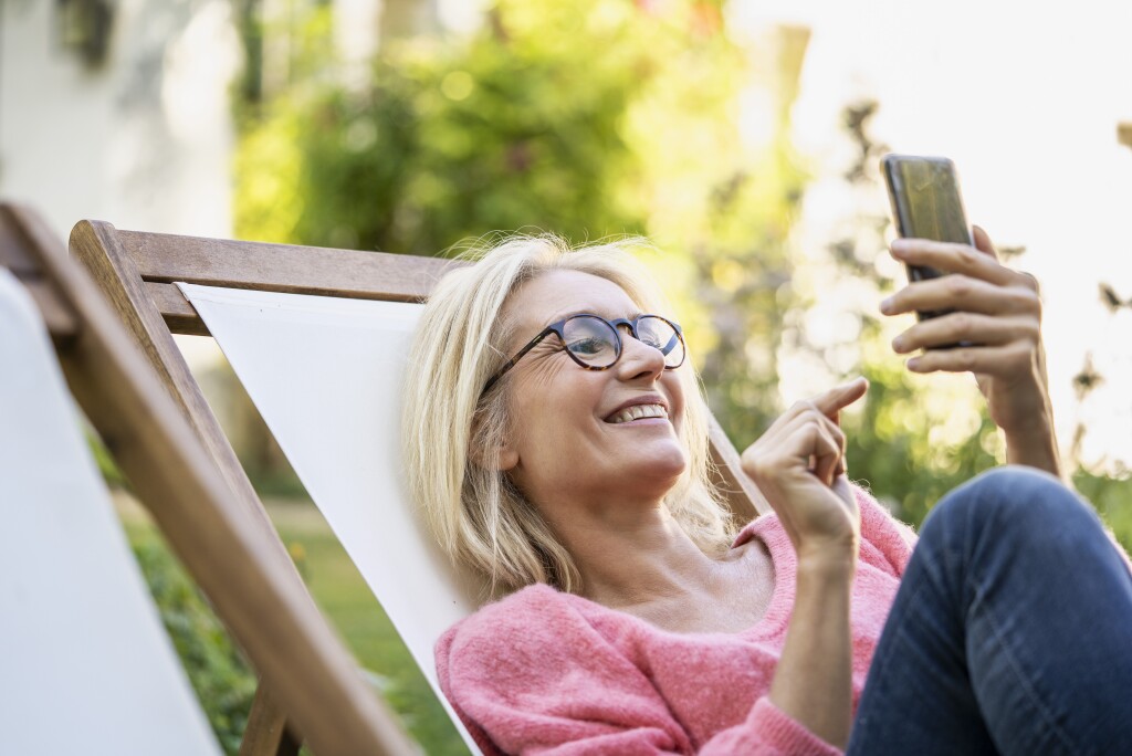 Woman on lawn chair using mobile