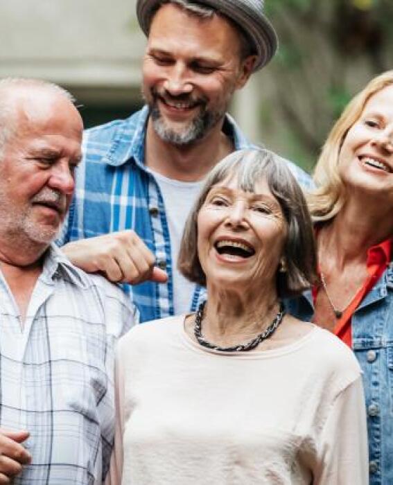 A diverse group of people standing in front of a wall and smiling together