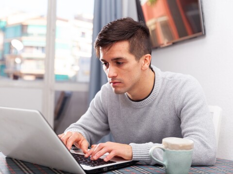 Man is working with laptop sitting at the table