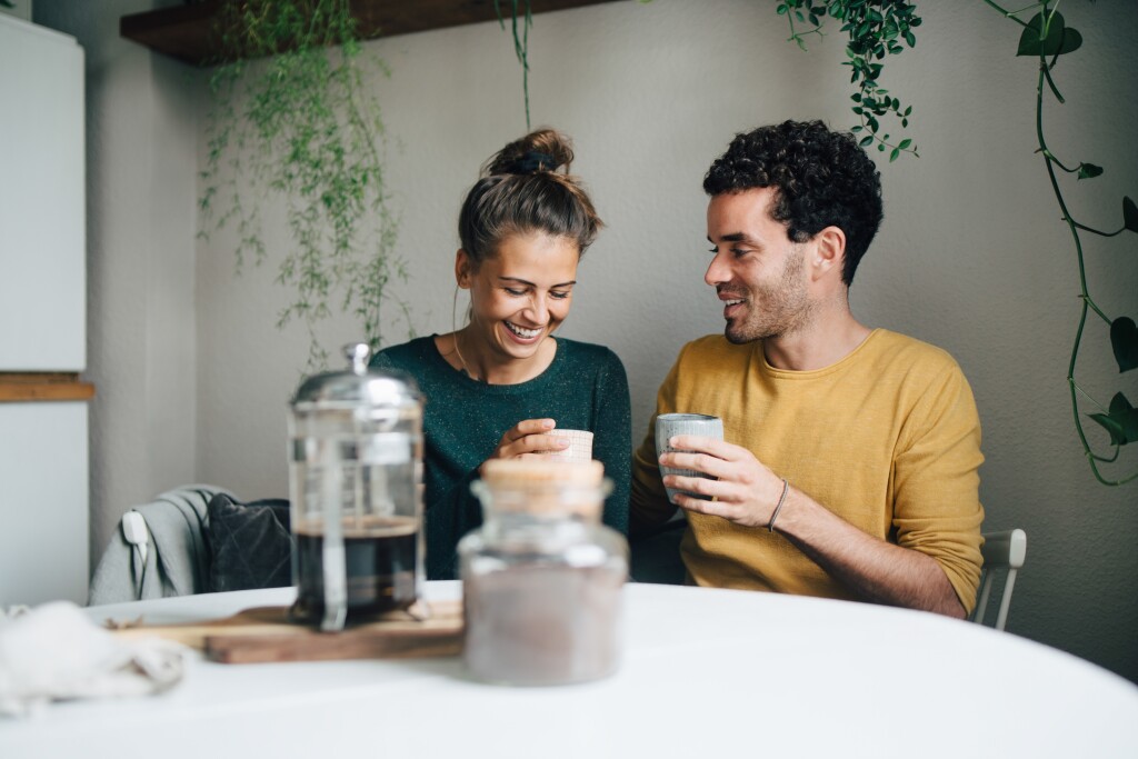 Smiling couple having coffee at table in living room