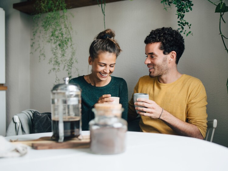 Smiling couple having coffee at table in living room