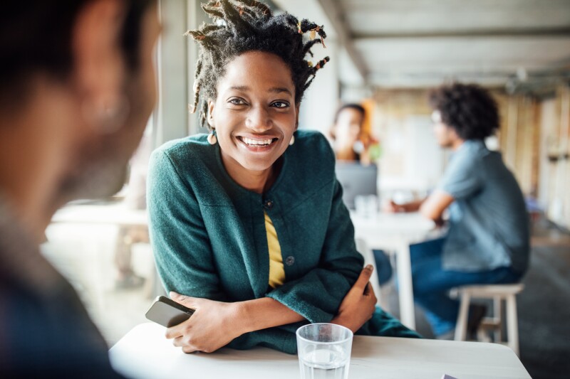Smiling businesswoman sitting with colleague in cafeteria