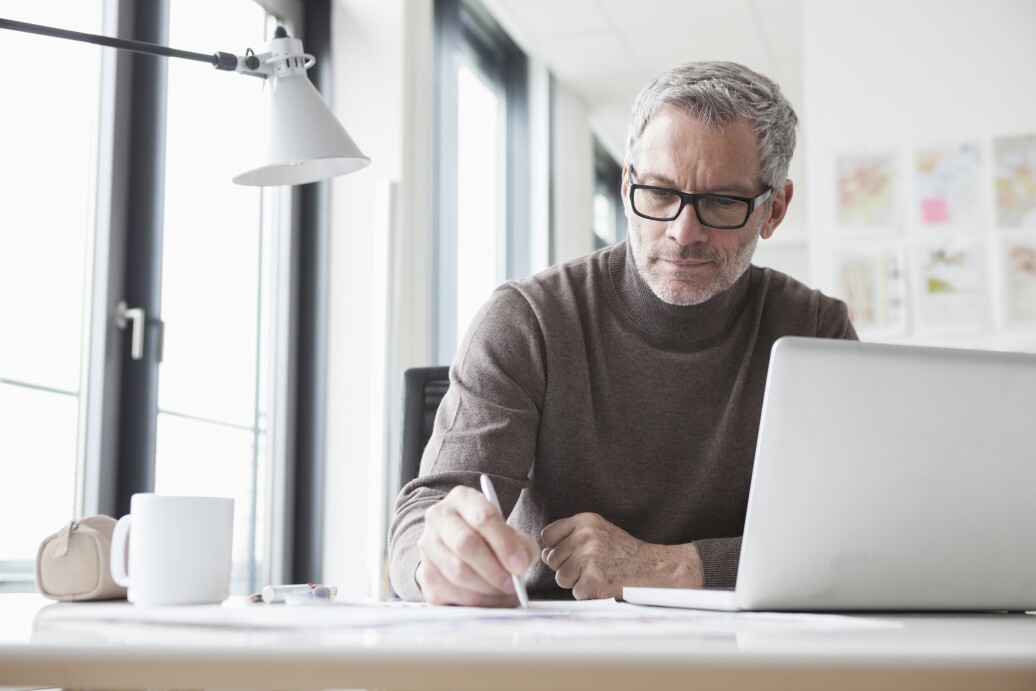 Mature man sitting in office using laptop