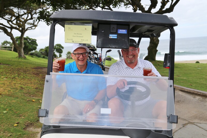 two men in golf cart smiling