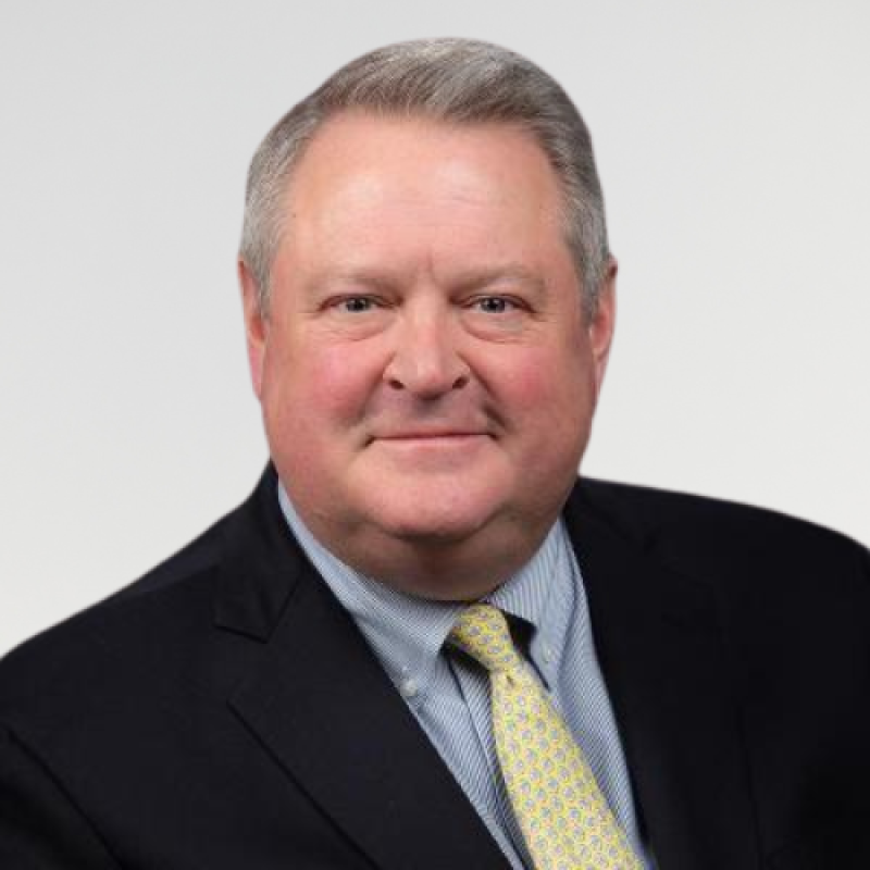 Head shot photo for Dr. Kirk Farney, wearing a navy suit, blue and white striped shirt and yellow tie