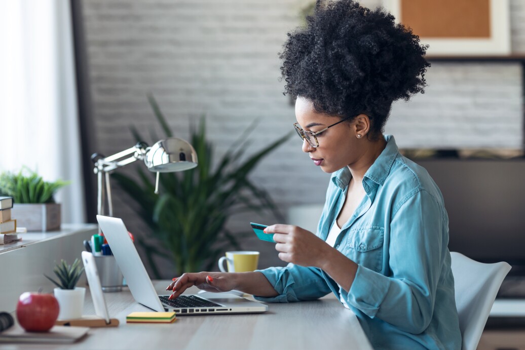 Woman looking at credit card and computer