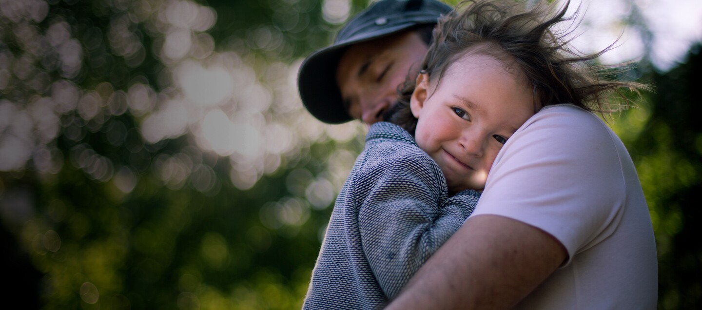 Toddler being held by dad while the wind blows their hair