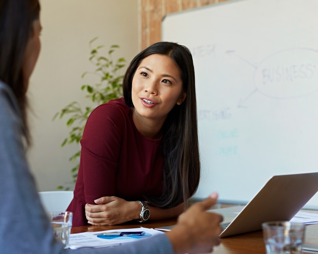 Woman talking to a colleague in front of a laptop