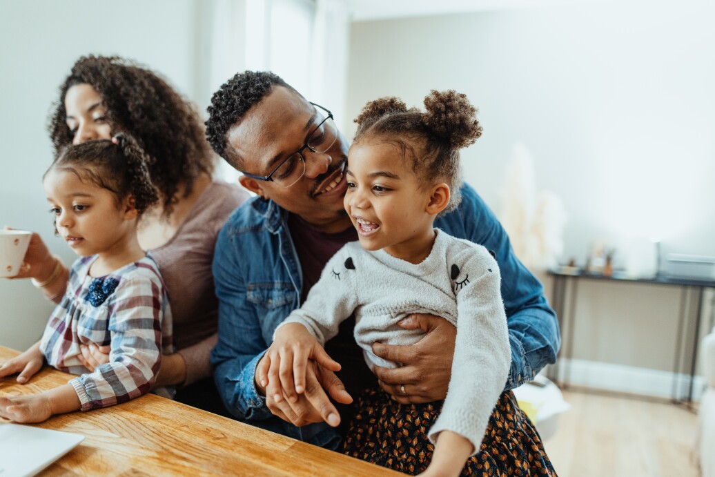 Multiracial family with two daughters at home. Father playing and laughing with elder daughter