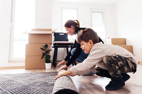 Mother and son rolling up a rug preparing for a move
