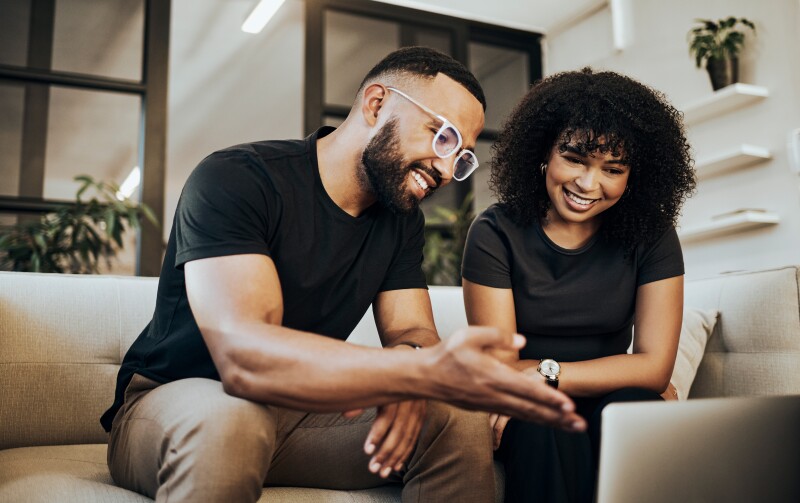 Couple in the living room of their home together looking at a laptop