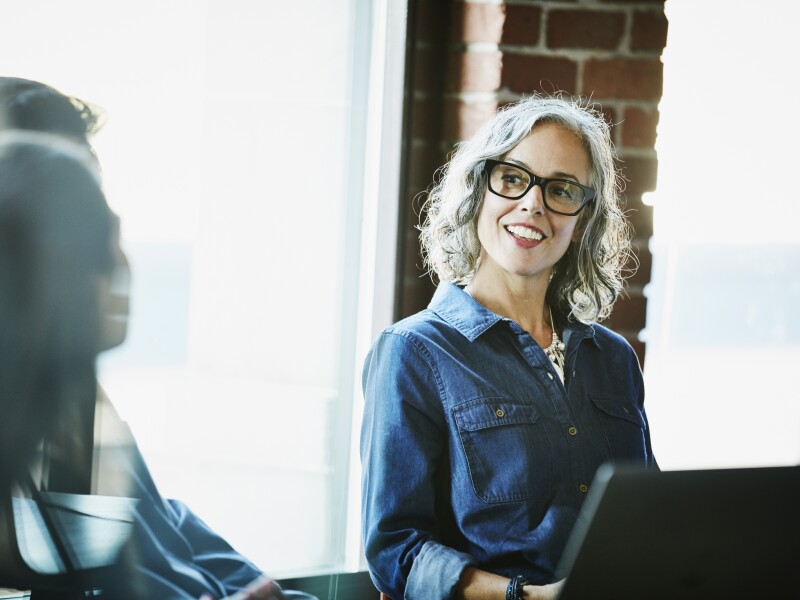 Smiling businesswoman leading meeting with clients in conference room