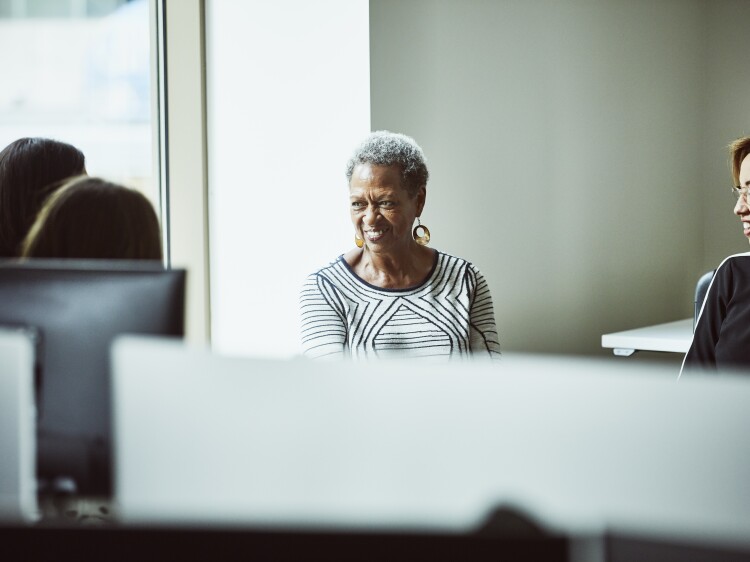 Smiling businesswoman leading informal team meeting at office workstation