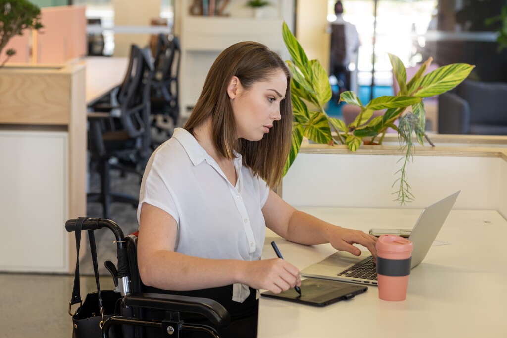 Young Woman In Wheelchair Working In Modern Office