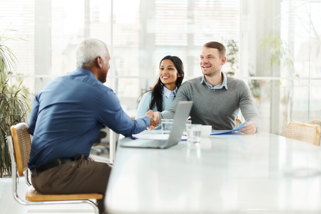 Happy  couple shaking hands with insurance agent in the office.