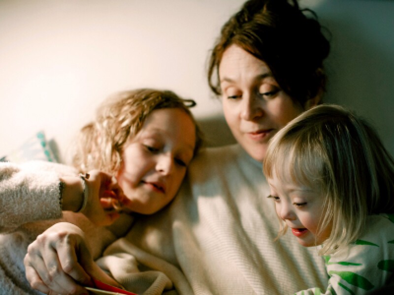 Mother reading to daughters in bedroom