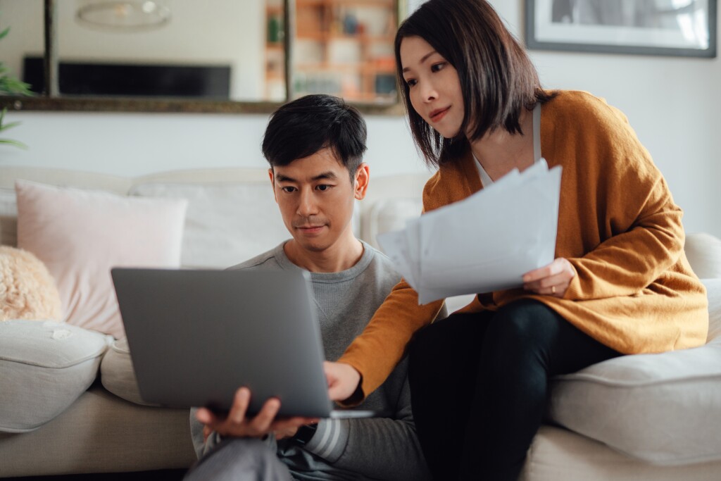 Young couple discussing over financial bills while using laptop on sofa