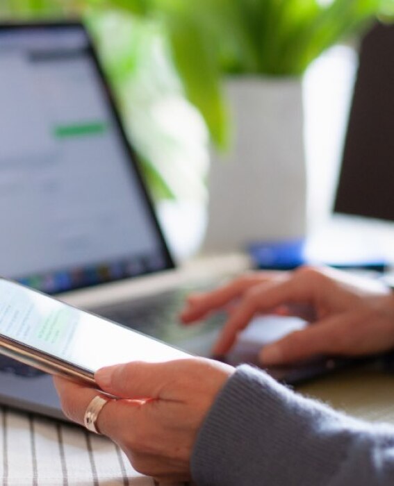 Photo of person using their phone in front of a laptop