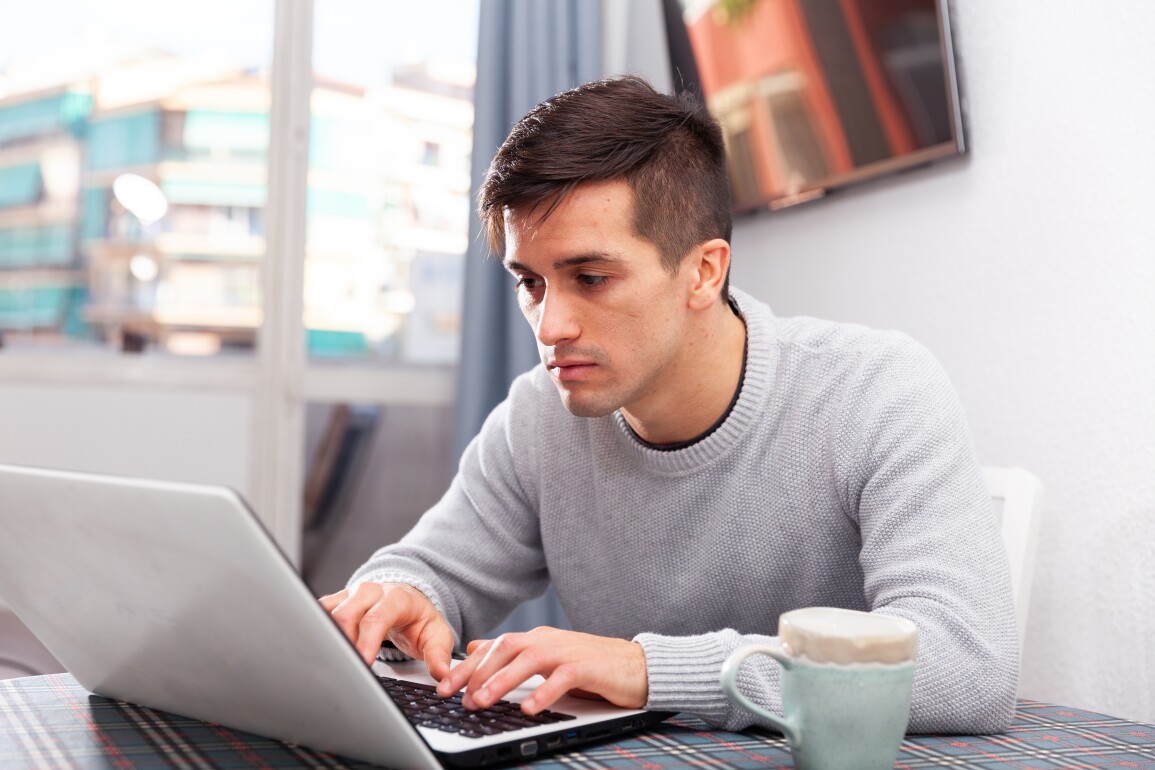 Man is working with laptop sitting at the table