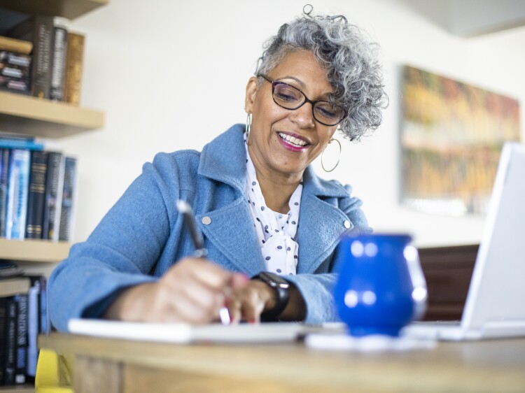 A beautiful mature black woman with gray hair working from home.