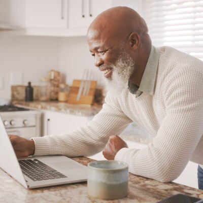 Happy senior guy, computer and working in house
