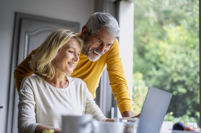 Couple around 60 looking at laptop