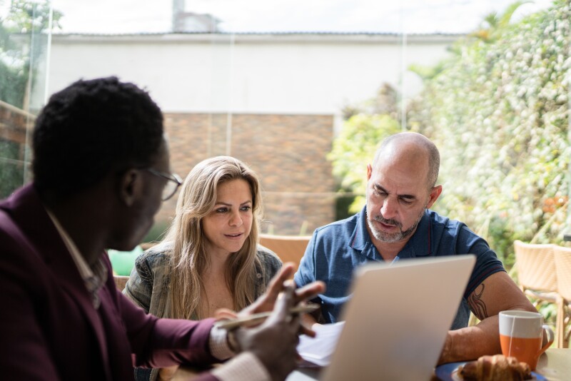 Financial advisor showing contract to couple at home during business meeting