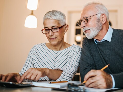 Mature couple doing some paperwork and calculations at home