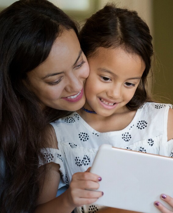 Mother smiling with her daughter looking at a tablet