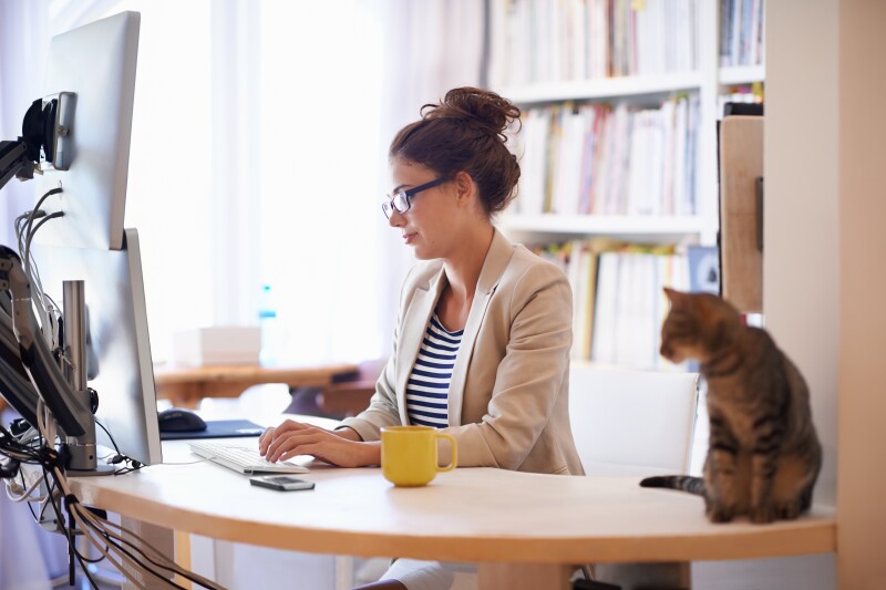 Woman sitting at desk with her cat by her side.