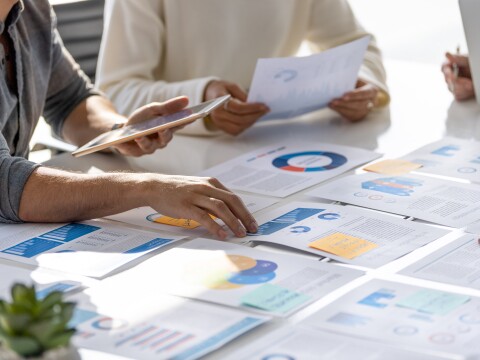 Multi racial group of people working with Paperwork on a board room table at a business presentation or seminar.