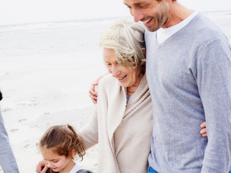 Happy family with grandmother walking on the beach