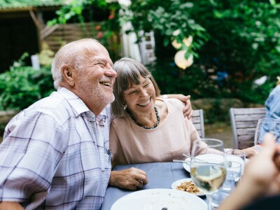 Middle-aged couple enjoying dinner outside with a few others