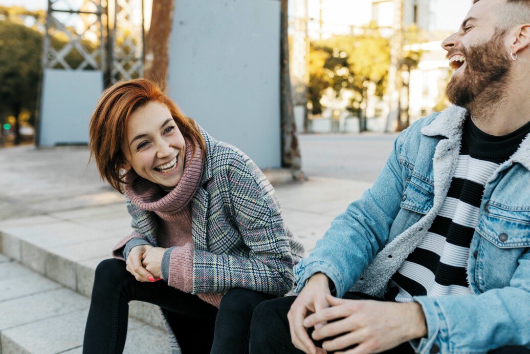 Happy couple sitting outdoors laughing