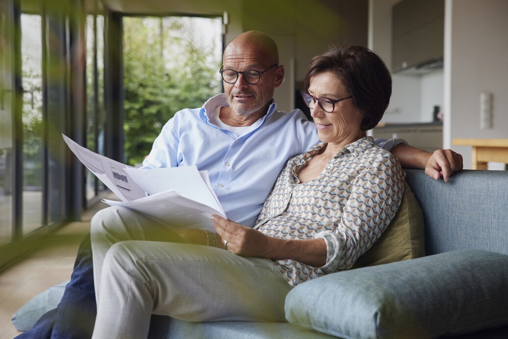 Smiling man with woman reading documents at home