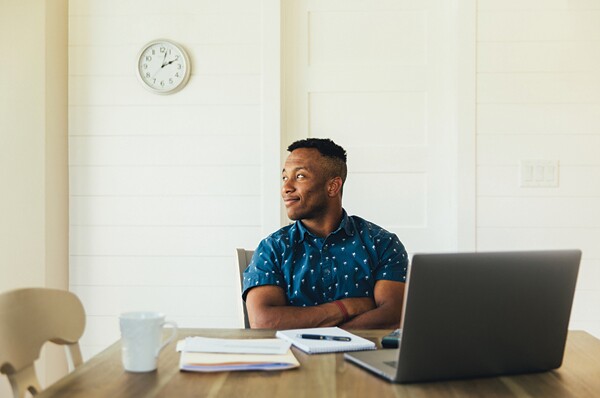 Man sitting at computer smiling with arms crossed