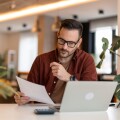 Millennial man using laptop sitting at the table in a home office