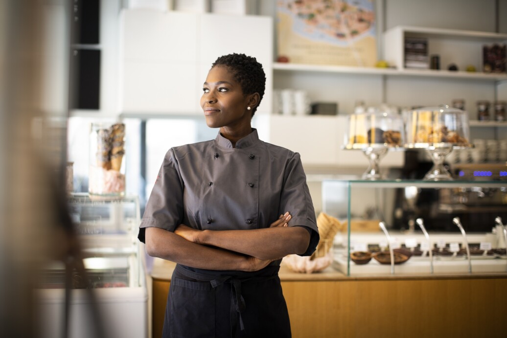 Smiling chef with arms crossed looking away in a bakery