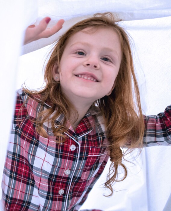 Child smiling under a white sheet