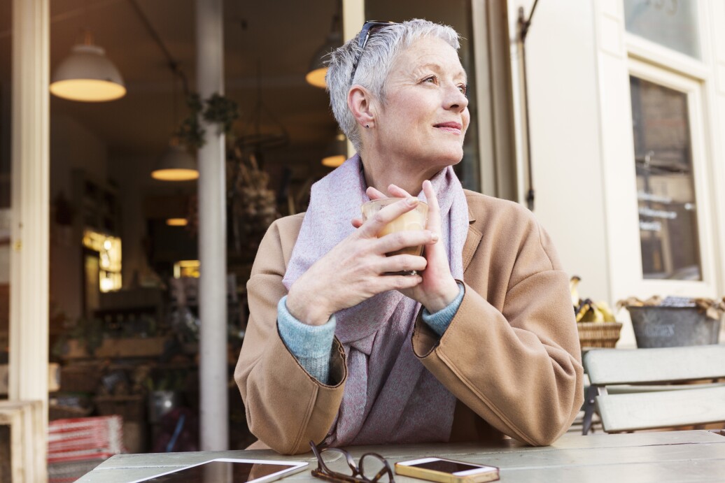 Senior woman having a coffee outside in cafe.