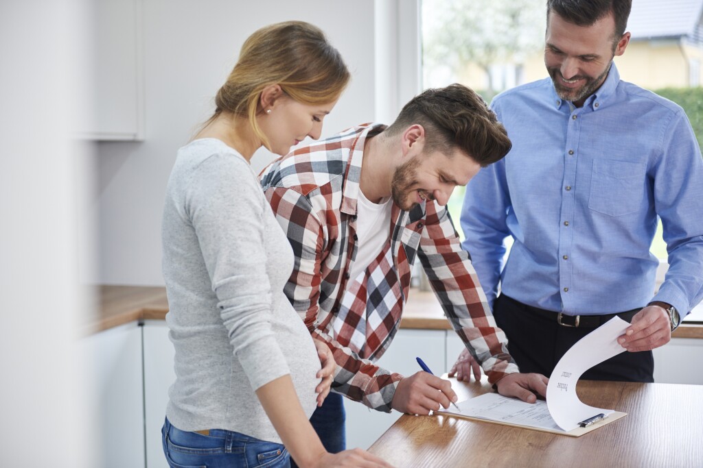 Pregnant couple signing papers with a professional