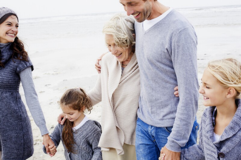 Happy family with grandmother walking on the beach
