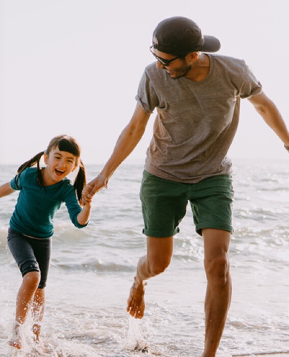 Father running on the beach with his daughter
