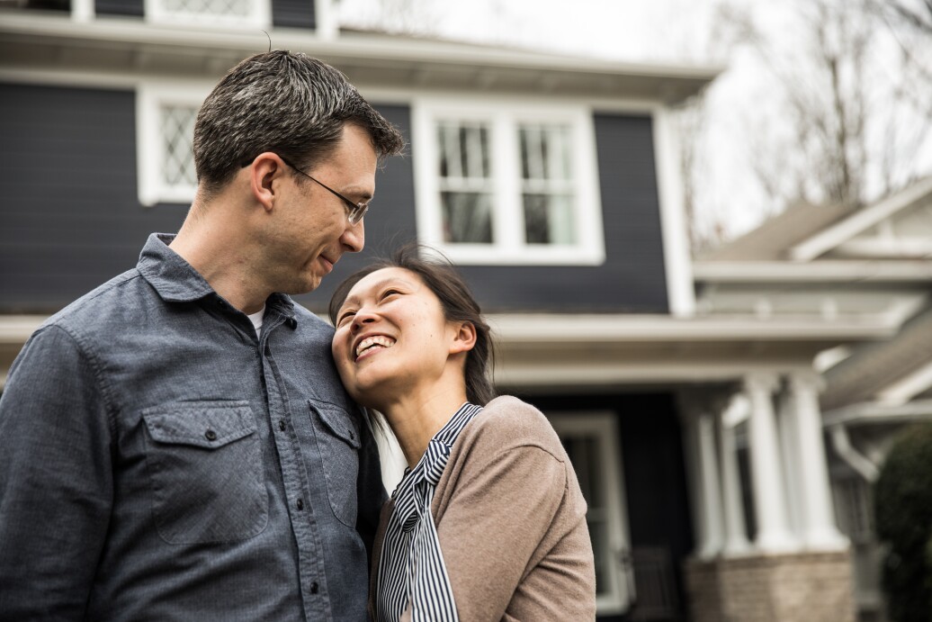 Couple standing in front of home looking happy