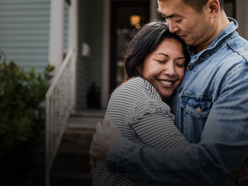Happy couple embracing in front of a home